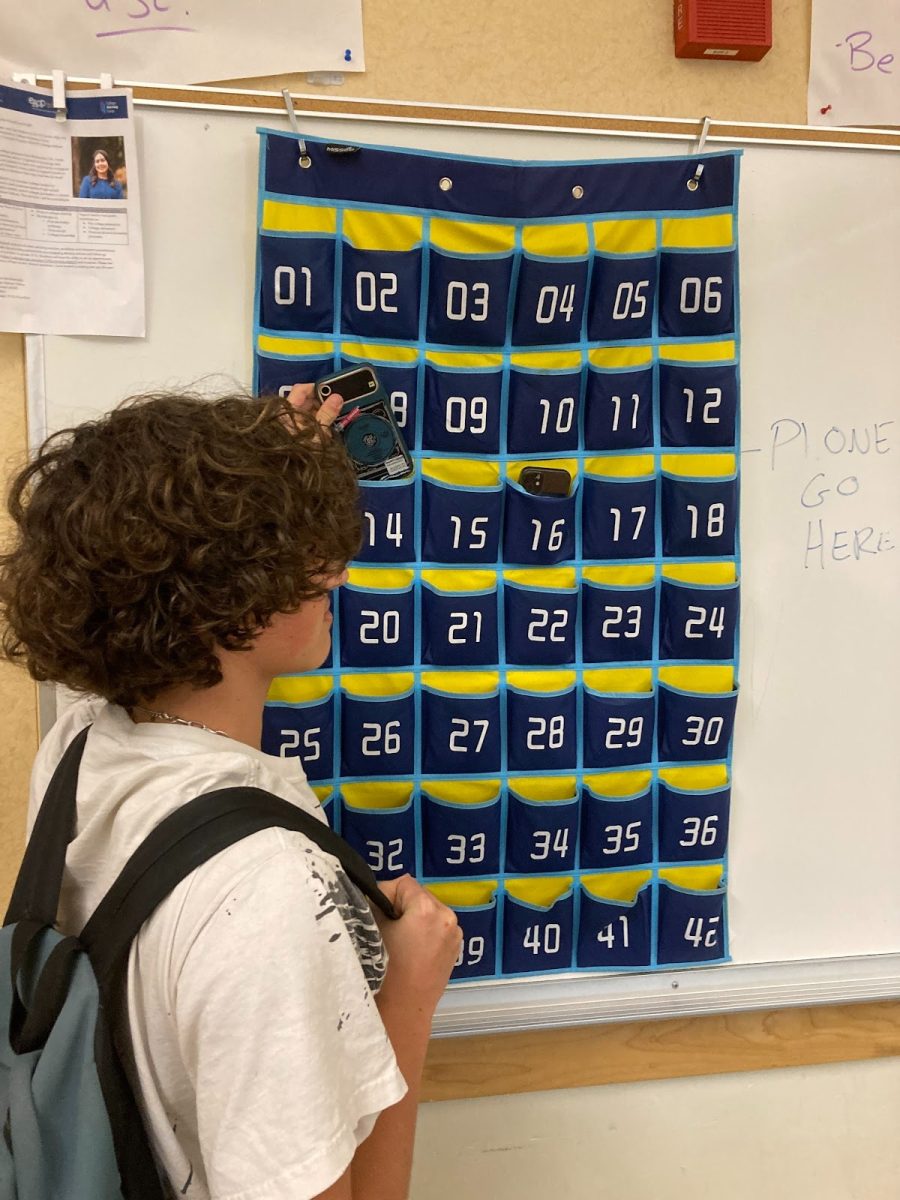 An El Cerrito High School student puts his phone in his assigned pouch before class begins. Many teachers now require students to stow phones in pouches during class, while others allow them to be stowed in backpacks.