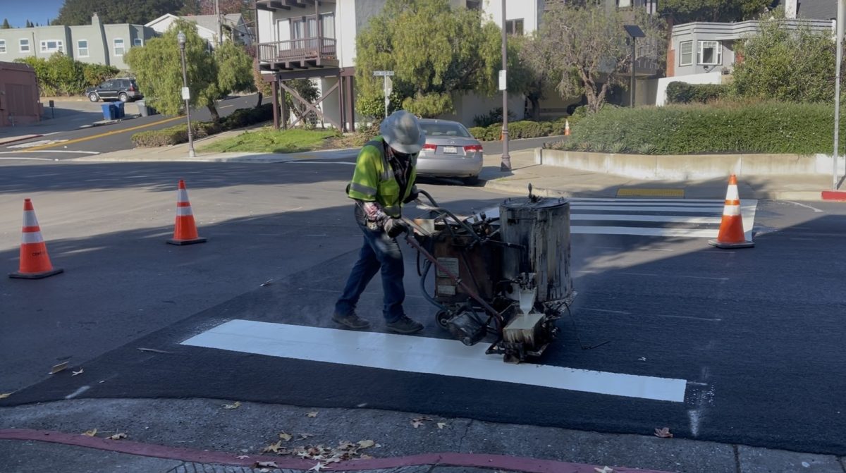 Worker repaints crosswalk on Colusa Avenue in Kensington after road was repaved as part of the Contra Costa Public Works'  Slurry Seal Project to fix roads in unincorporated areas. 