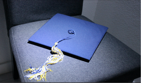 A graduation cap sits on an empty chair, symbolizing students who graduate early and are absent from the pomp and circumstance of the traditional graduation ceremony. 