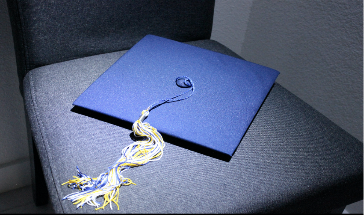 A graduation cap sits on an empty chair, symbolizing students who graduate early and are absent from the pomp and circumstance of the traditional graduation ceremony. 