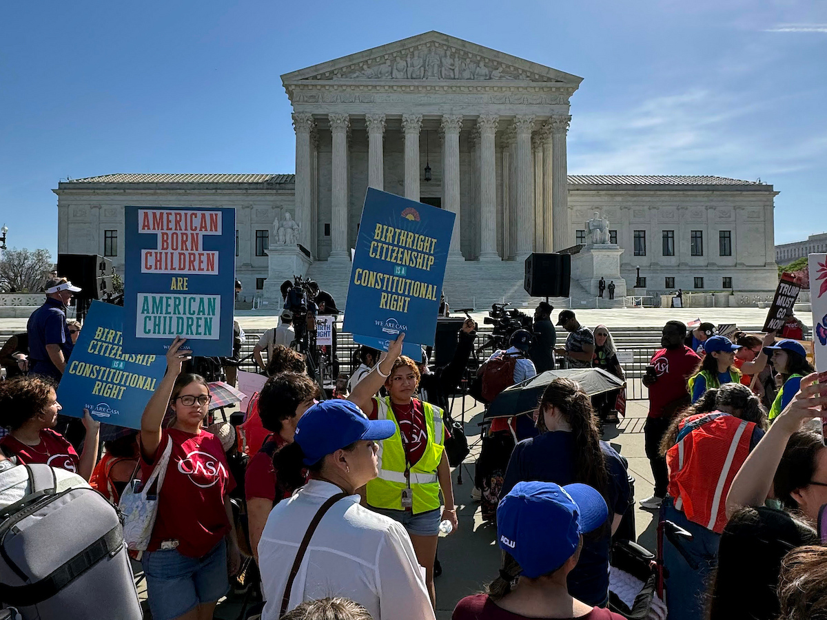 A group of people hold signs advocating for birthright citizenship in front of the U.S. Supreme Court building on a sunny day.